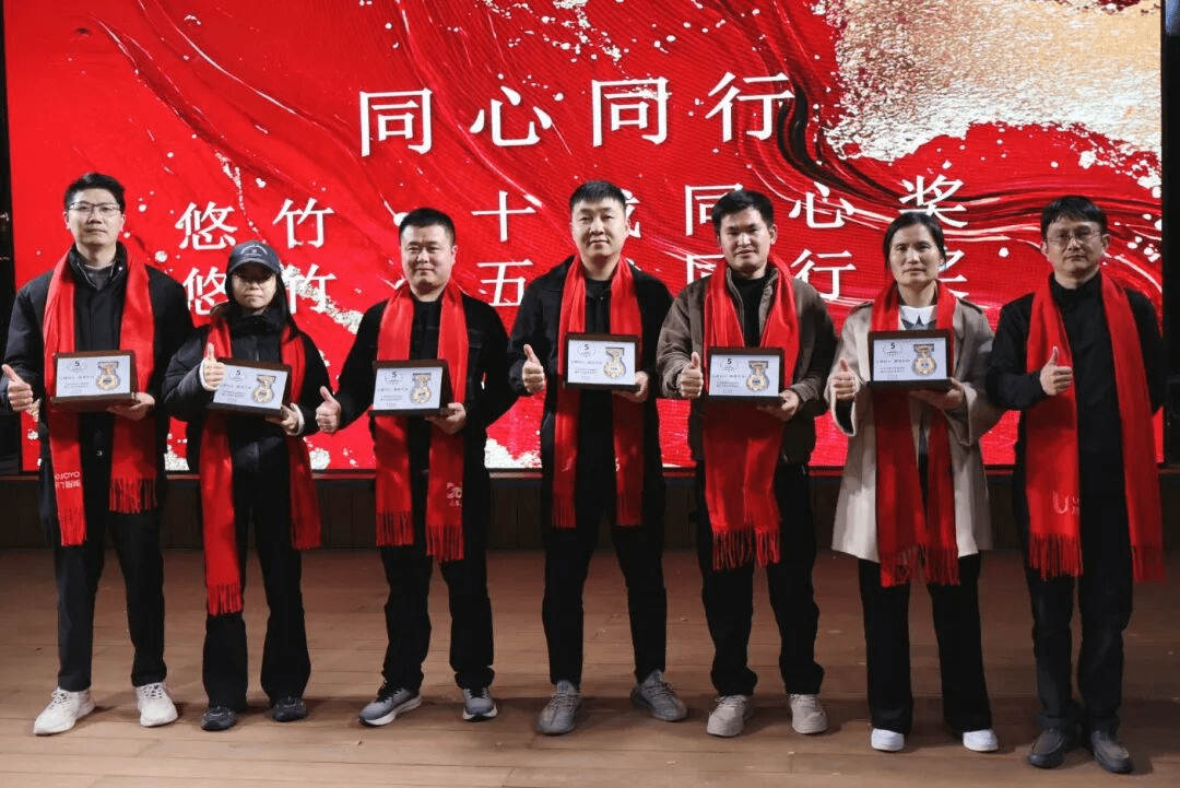 获奖同事在颁奖典礼上合影,身穿黑色服装佩戴红色围巾,手持奖牌