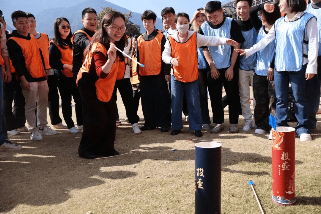 团队成员穿着橙色和蓝色背心参与投壶游戏活动