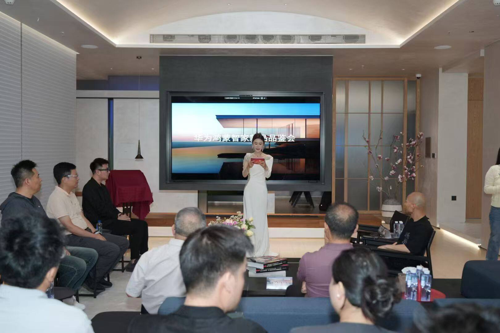 品鉴会现场,白色礼服主持人在大屏幕前主持活动,台下坐满嘉宾