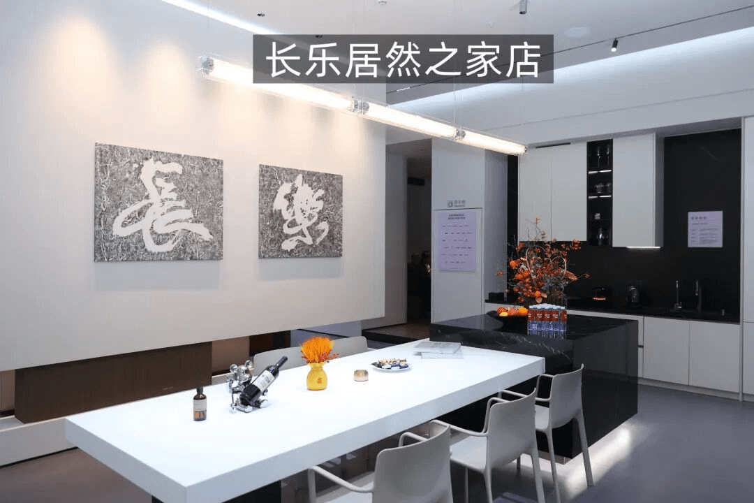 长乐居然之家店内部展示,现代简约风格的餐厅场景,白色长桌、灰色椅子,墙上挂着长乐书法作品